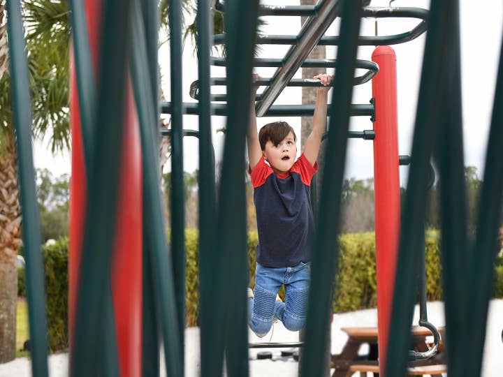 Child hanging from monkey bars at playground in Orange Lake Resort near Orlando, Florida.