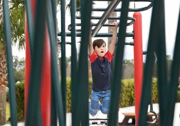 Child hanging from monkey bars at playground in Orange Lake Resort near Orlando, Florida.