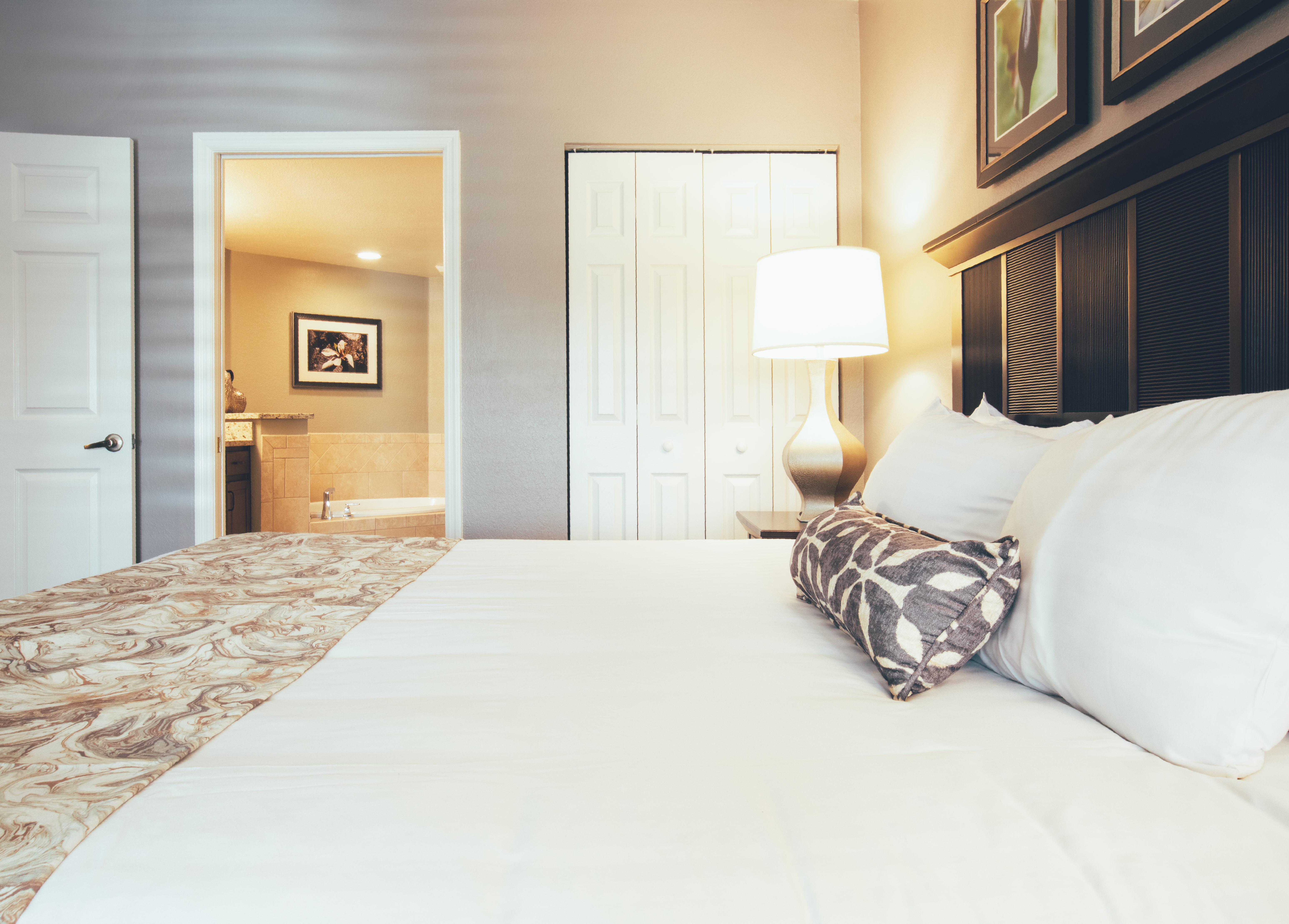 Closeup of a bed with view of attached bathroom in the background in a villa in North Village at Orange Lake Resort near Orlando, Florida