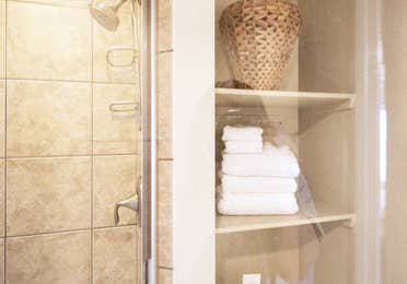 Closeup of walk-in shower and wall storage holding white folded towels in a Signature villa in River Island at Orange Lake Resort near Orlando, Florida