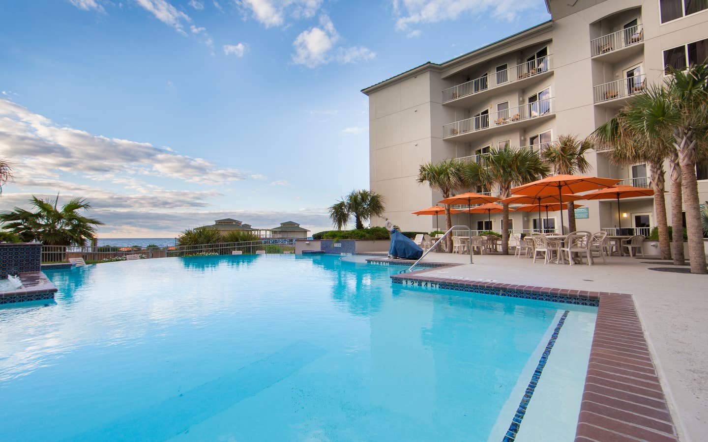 Outdoor pool surrounded by palm trees and umbrelles at Galveston Beach Resort.