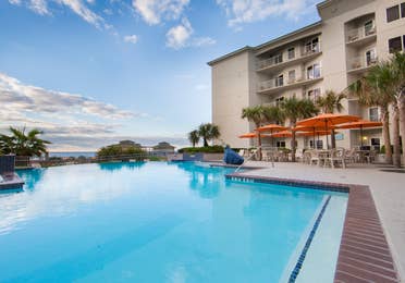 Outdoor pool surrounded by palm trees and umbrelles at Galveston Beach Resort.
