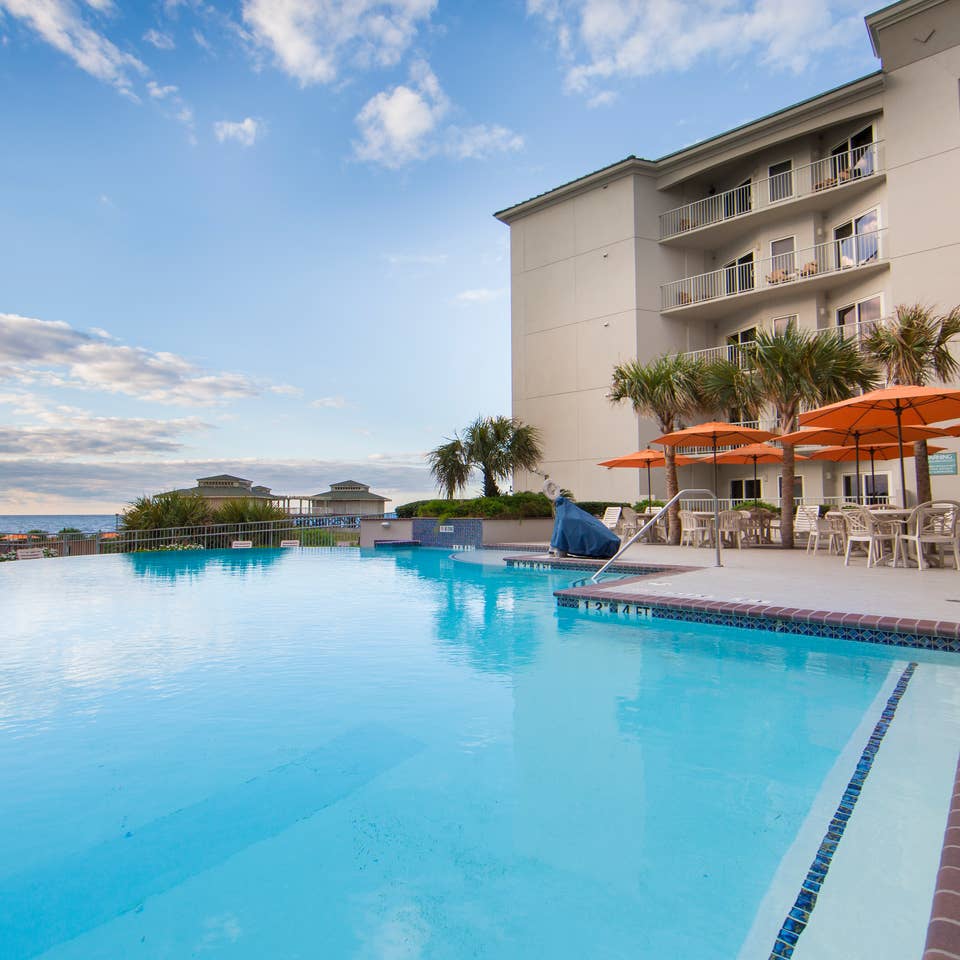 Outdoor pool surrounded by palm trees and umbrelles at Galveston Beach Resort.