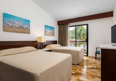 Modern bedroom with two twin beds, a window, and coastal artwork.