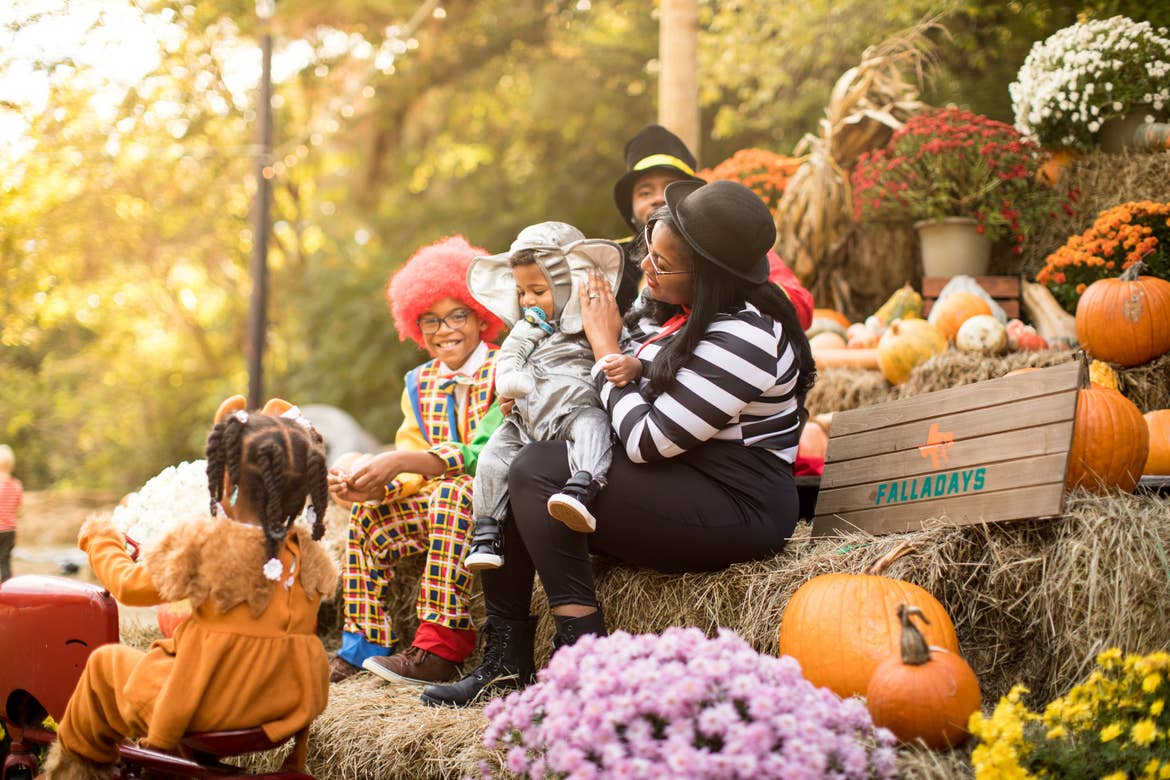 A family sits on haystacks wearing halloween costumes.