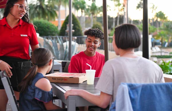 Family sitting outside looking at pizza box at Orange Lake Resort near Orlando, Florida