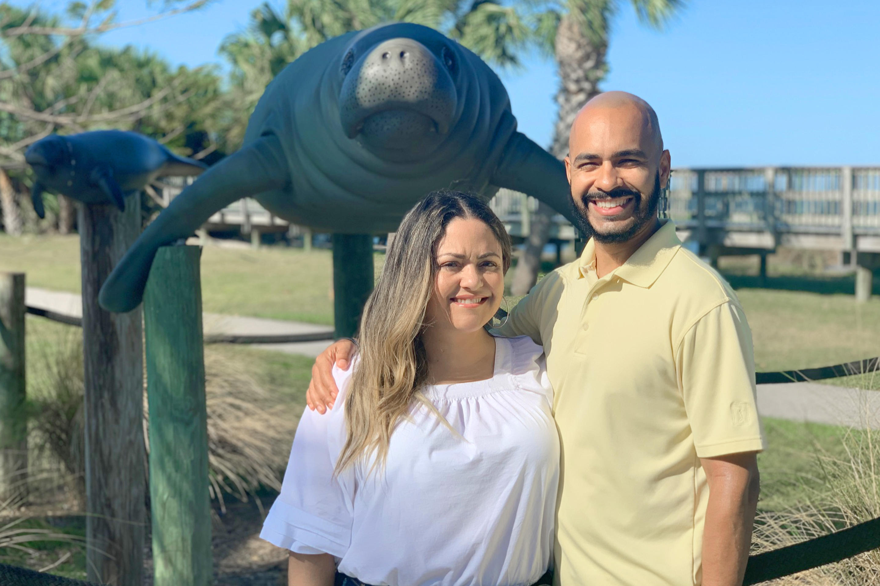 Val and her husband, Gio, stand in front of the manatee statues at Manatee Sanctuary Park.
