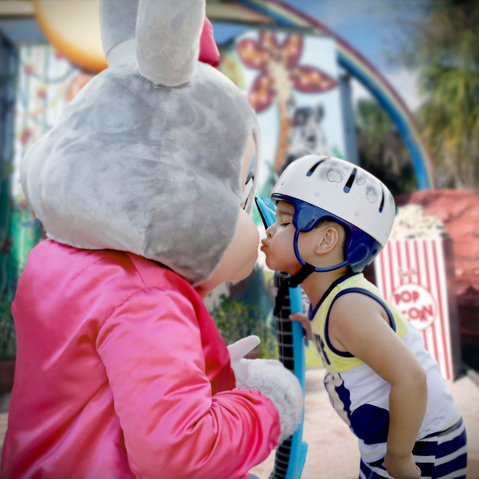 Boy wearing a helmet and giving a kiss to a bunny mascot