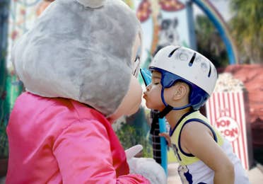 Boy wearing a helmet and giving a kiss to a bunny mascot