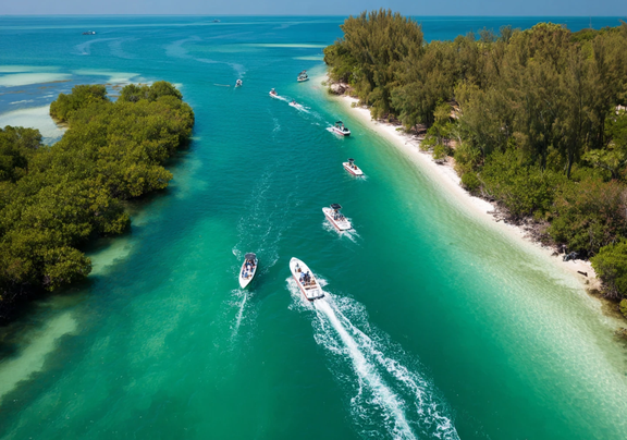 Drone view of boats in strait, gliding on aqua blue water and next to white sand.