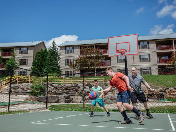 Dad and two sons playing basketball on outdoor sports courts at Oak n' Spruce Resort in South Lee, Massachusetts.