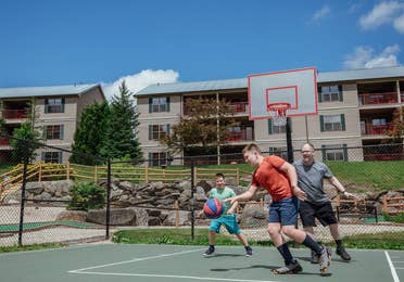Dad and two sons playing basketball on outdoor sports courts at Oak n' Spruce Resort in South Lee, Massachusetts.