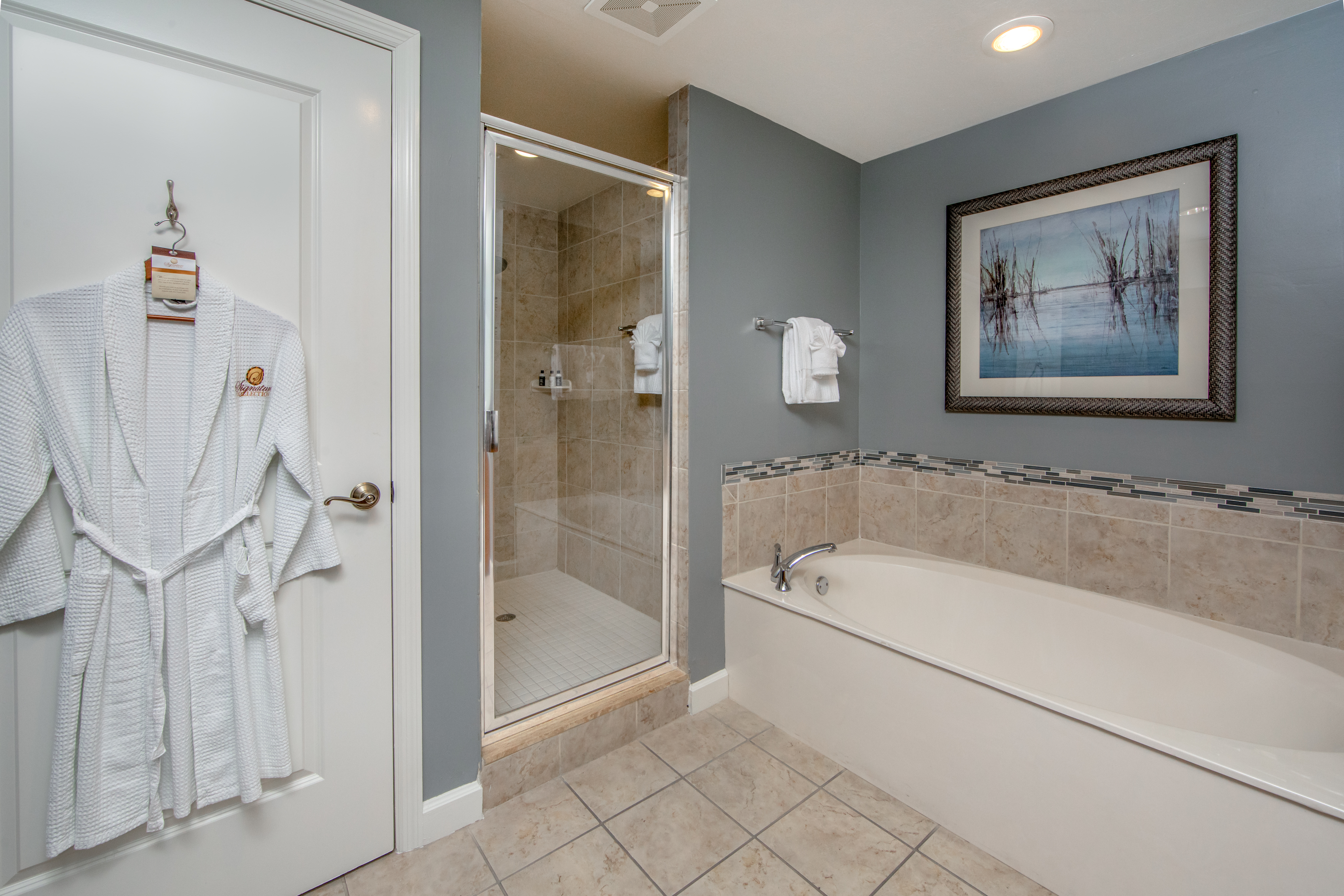 Bathroom with walk-in shower, bathtub, and robe in a three-bedroom villa at Sunset Cove Resort in Marco Island, Florida