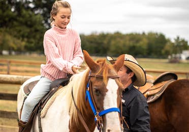 Child sitting on horse with adult supervising at Villages Resort in Flint, Texas.