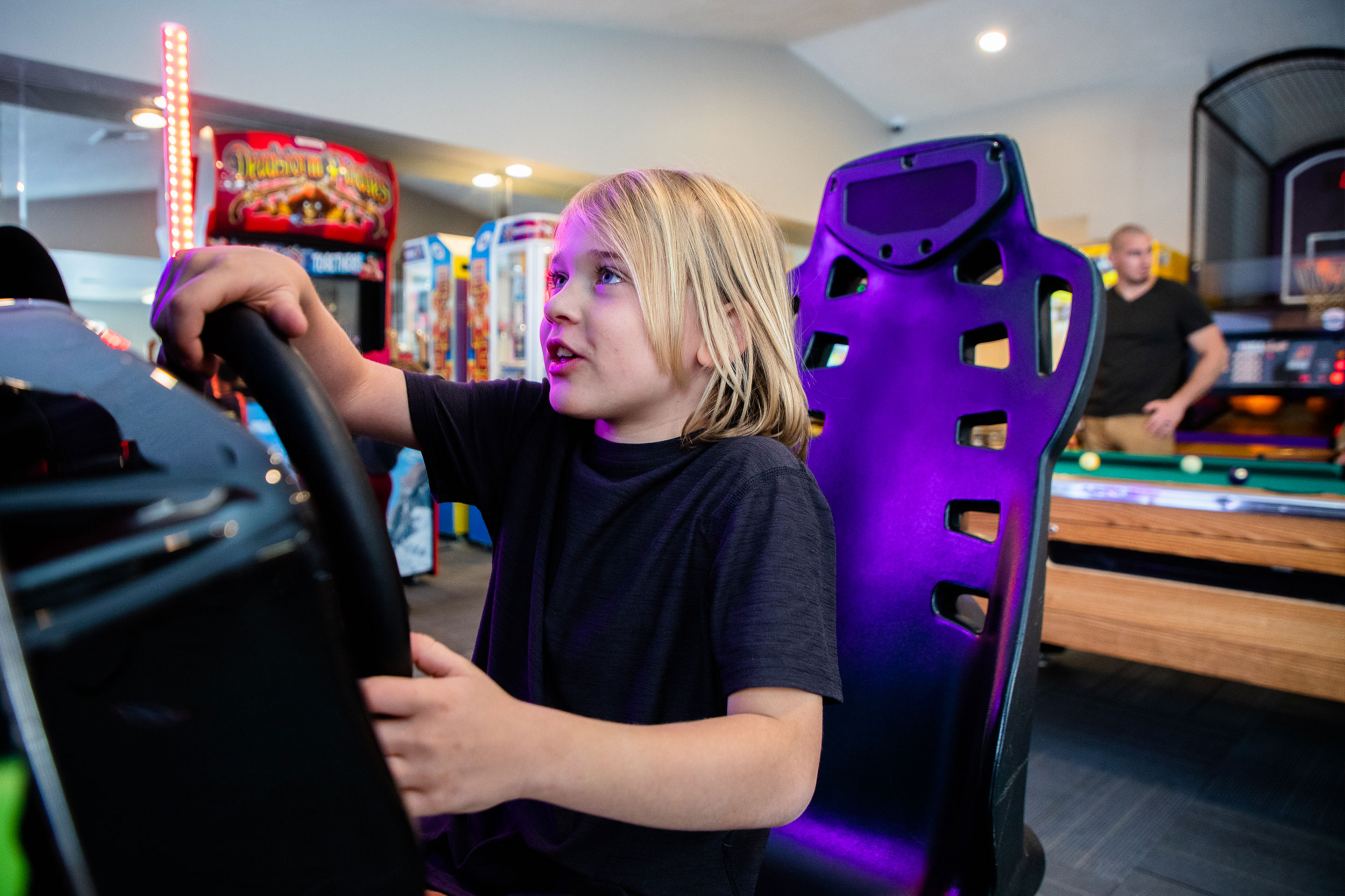 Featured author, Ashley Haby's son sits behind a steering wheel in the arcade of our Desert Club Resort located in Las Vegas, Nevada.