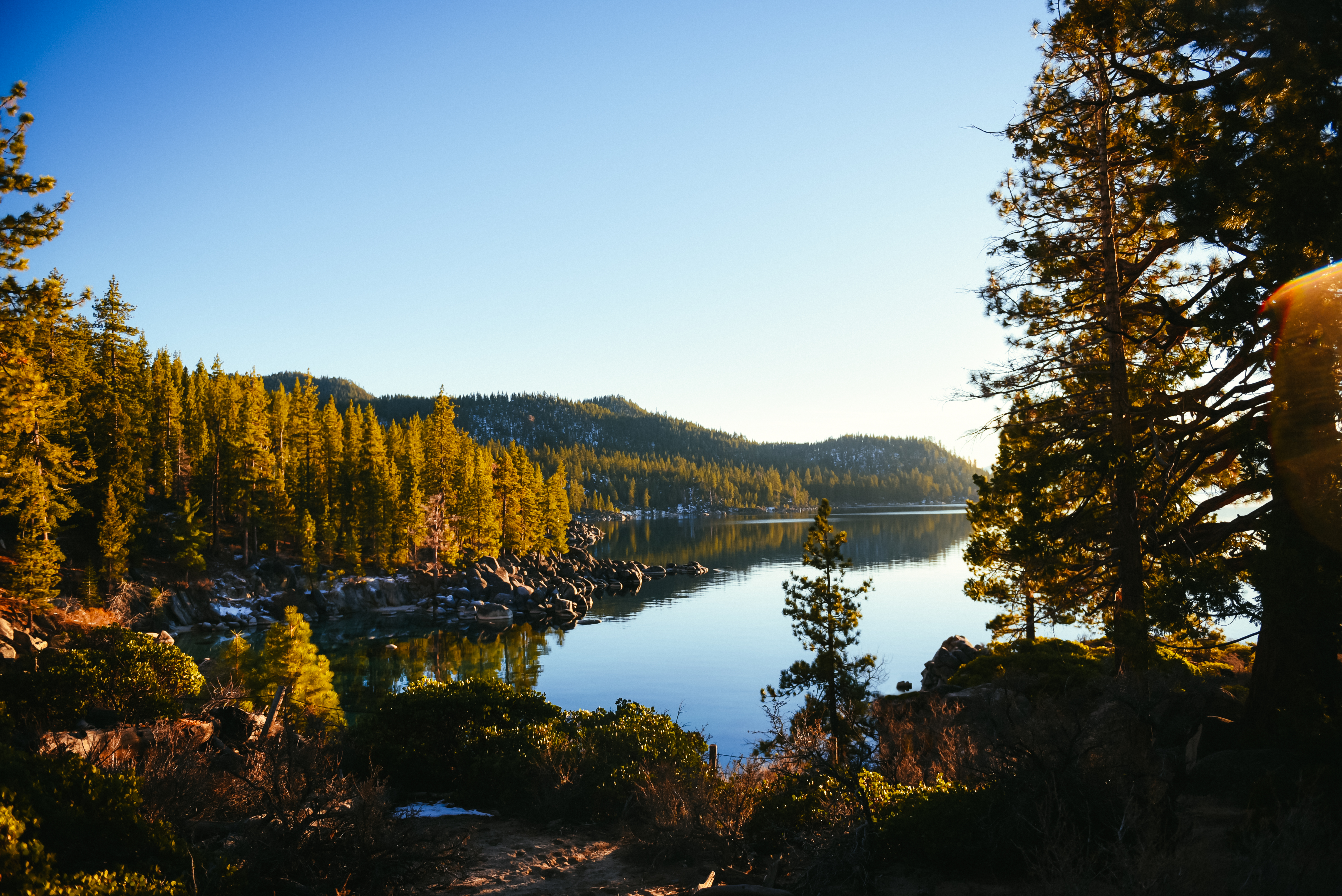 Lake Tahoe surrounded by orange fall foliage and mountains in the background