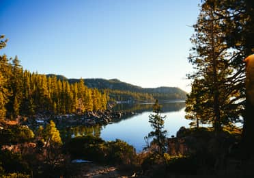 Lake Tahoe surrounded by orange fall foliage and mountains in the background