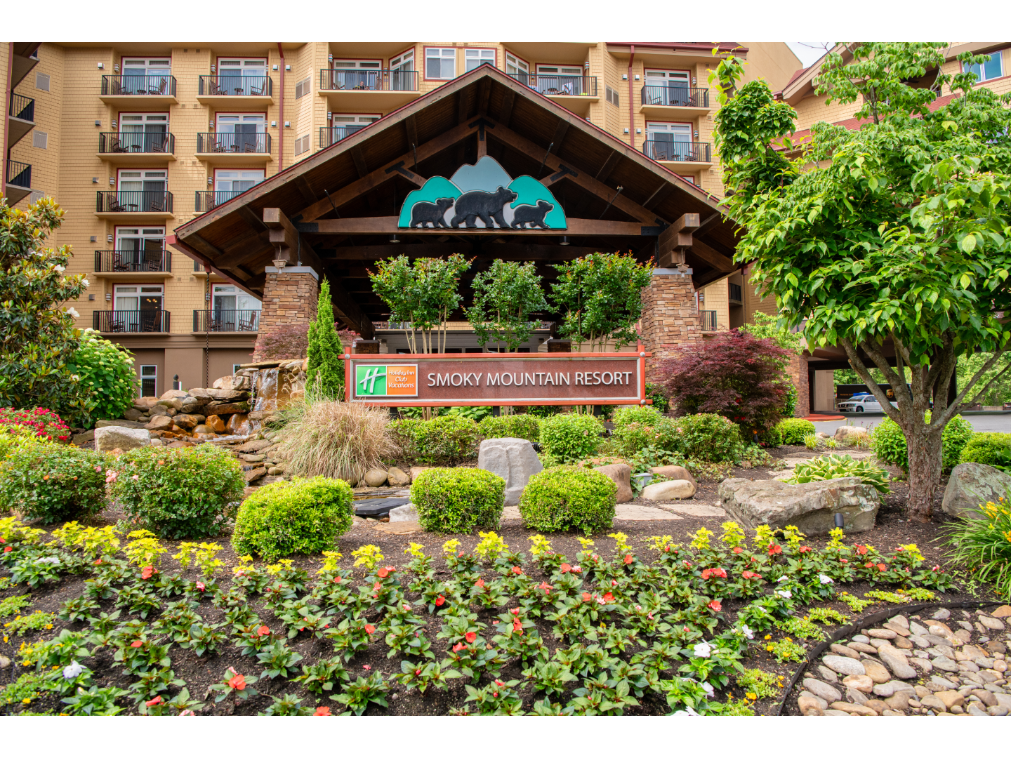 Sign in front of wooden lodge with lush green landscaping surrounding.