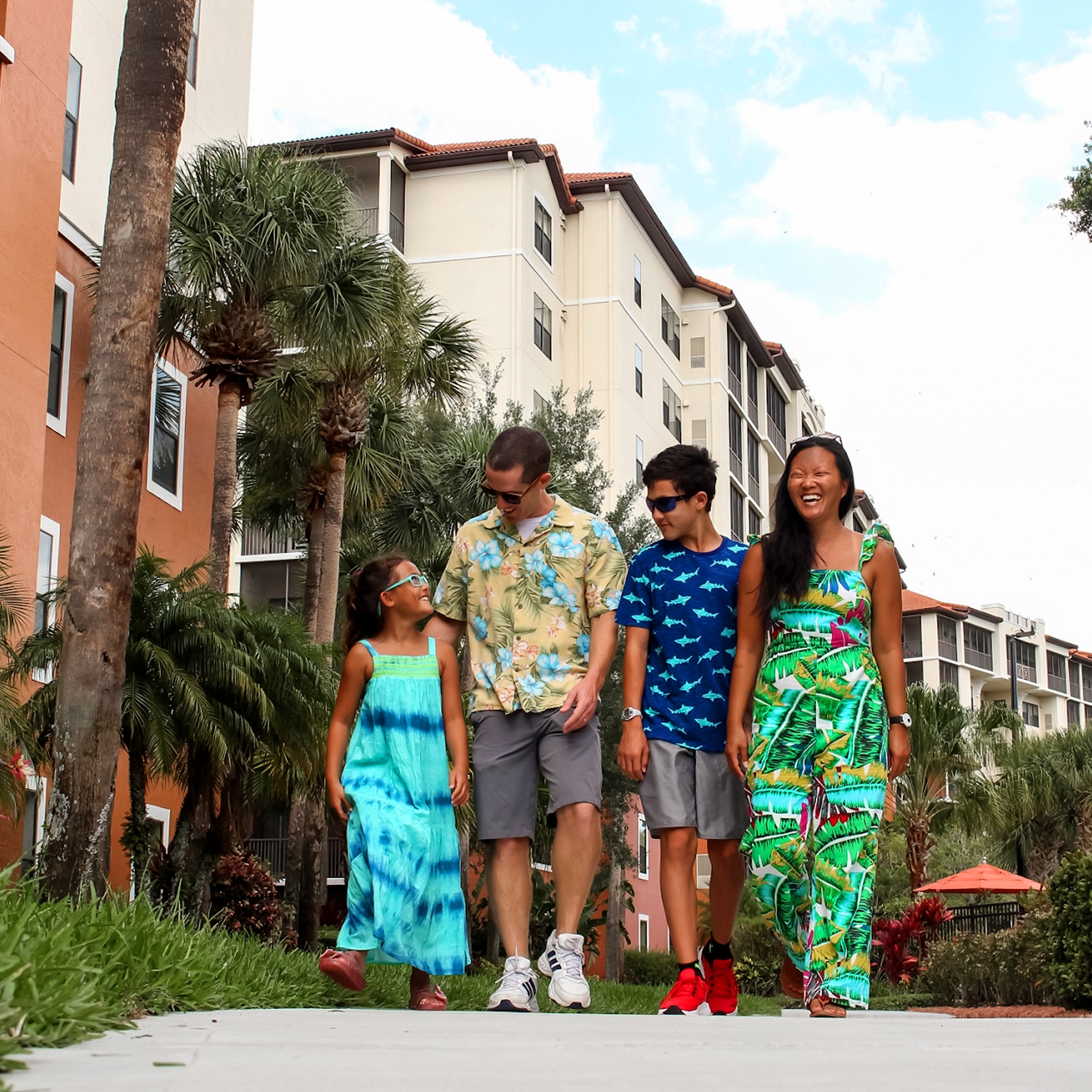 A family of four walk on a path near the exterior of our Orange Lake Resort located in Orlando, Florida.
