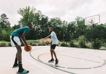 Two teens playing basketball on an outdoor court