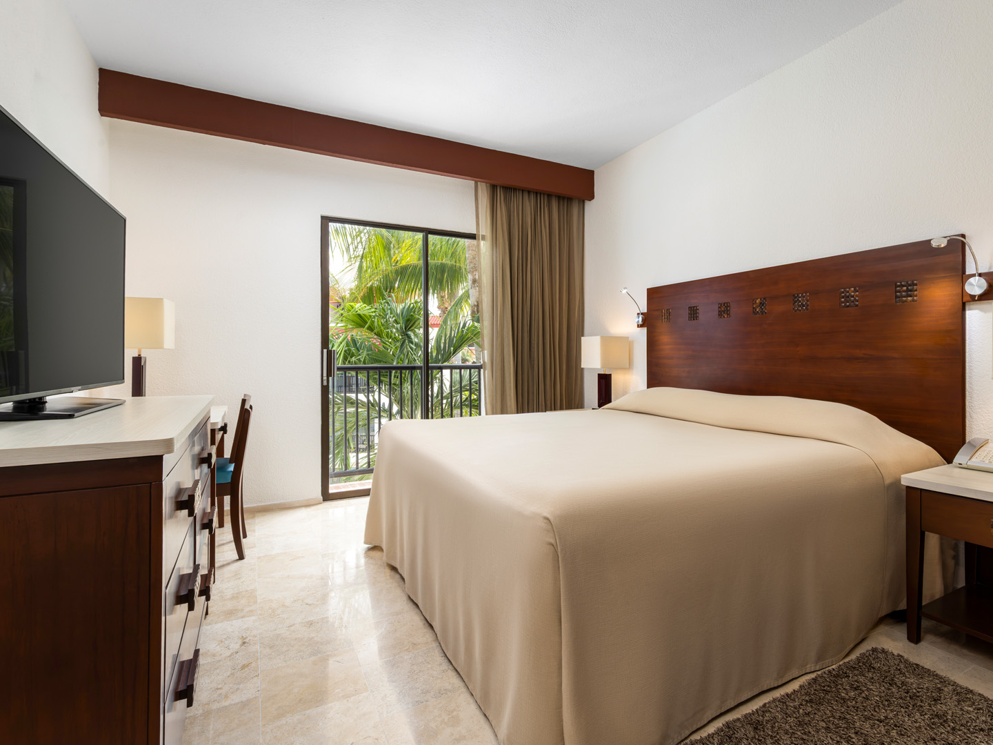 Suite bedroom with king bed and balcony overlooking gardens.