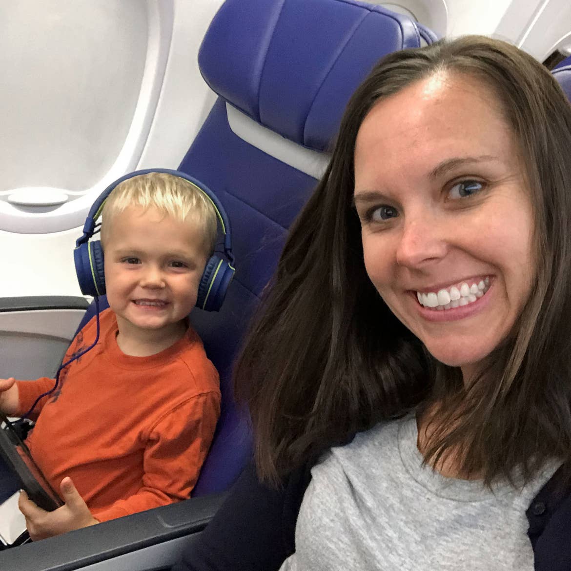 Author, Sarah, and son, Logan, sit near the window seat on their airplane pre-COVID.