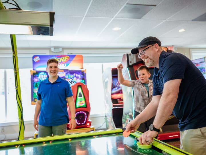 Dad and children playing air hockey at Oak n' Spruce Resort in South Lee, Massachusetts.