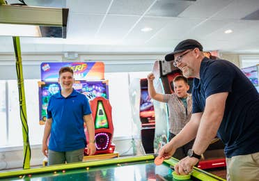 Dad and children playing air hockey at Oak n' Spruce Resort in South Lee, Massachusetts.