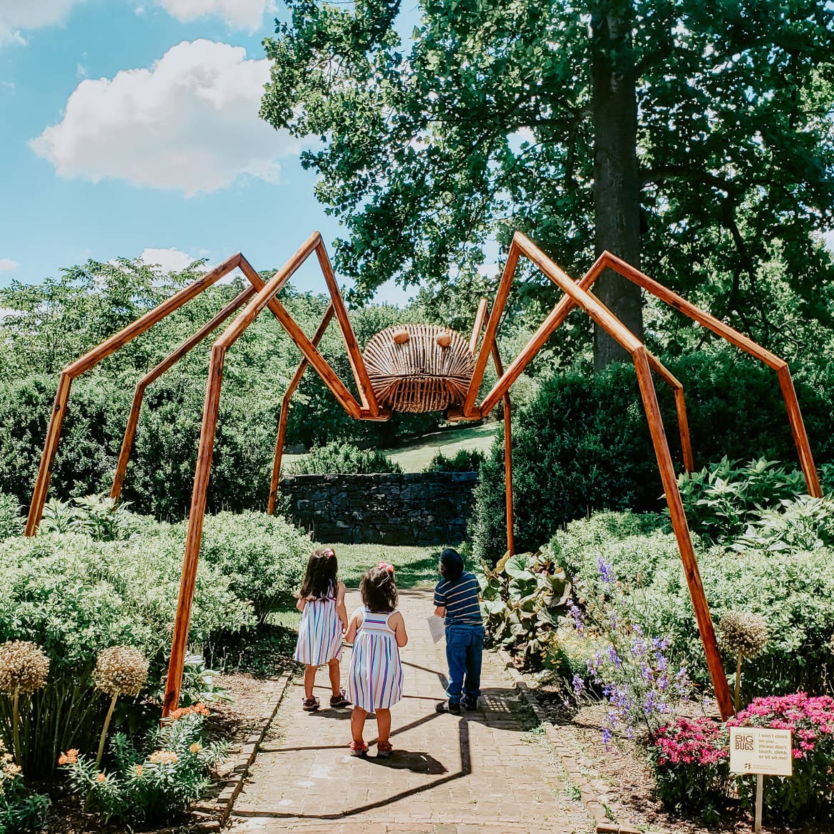Angelica's kids looking up at a giant wooden spider at the Big Bugs Sculpture Exhibit at the Museum of the Shenandoah Valley.