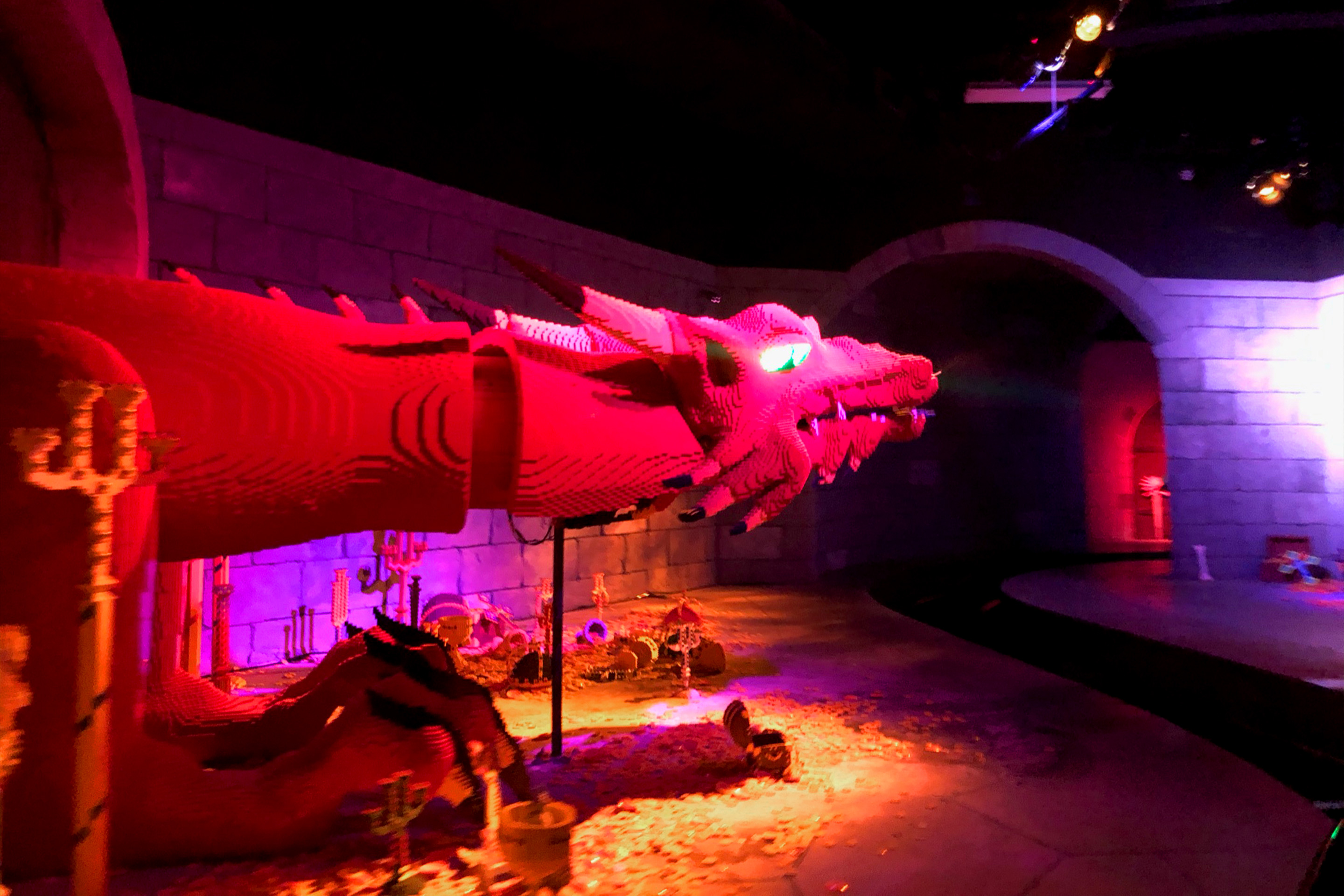 An oversized LEGO figure of a dragon sits indoors.