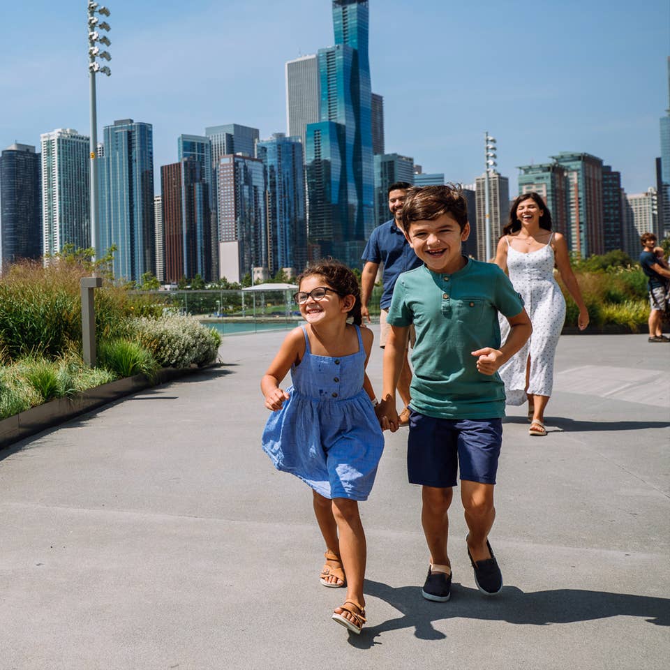 A woman, a man, a young boy and girl walk near the Chicago Skyline.