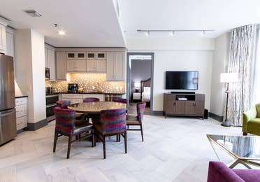 Signature Collection two bedroom villa living area with TV, dining area and full kitchen at New Orleans Resort in Louisiana.