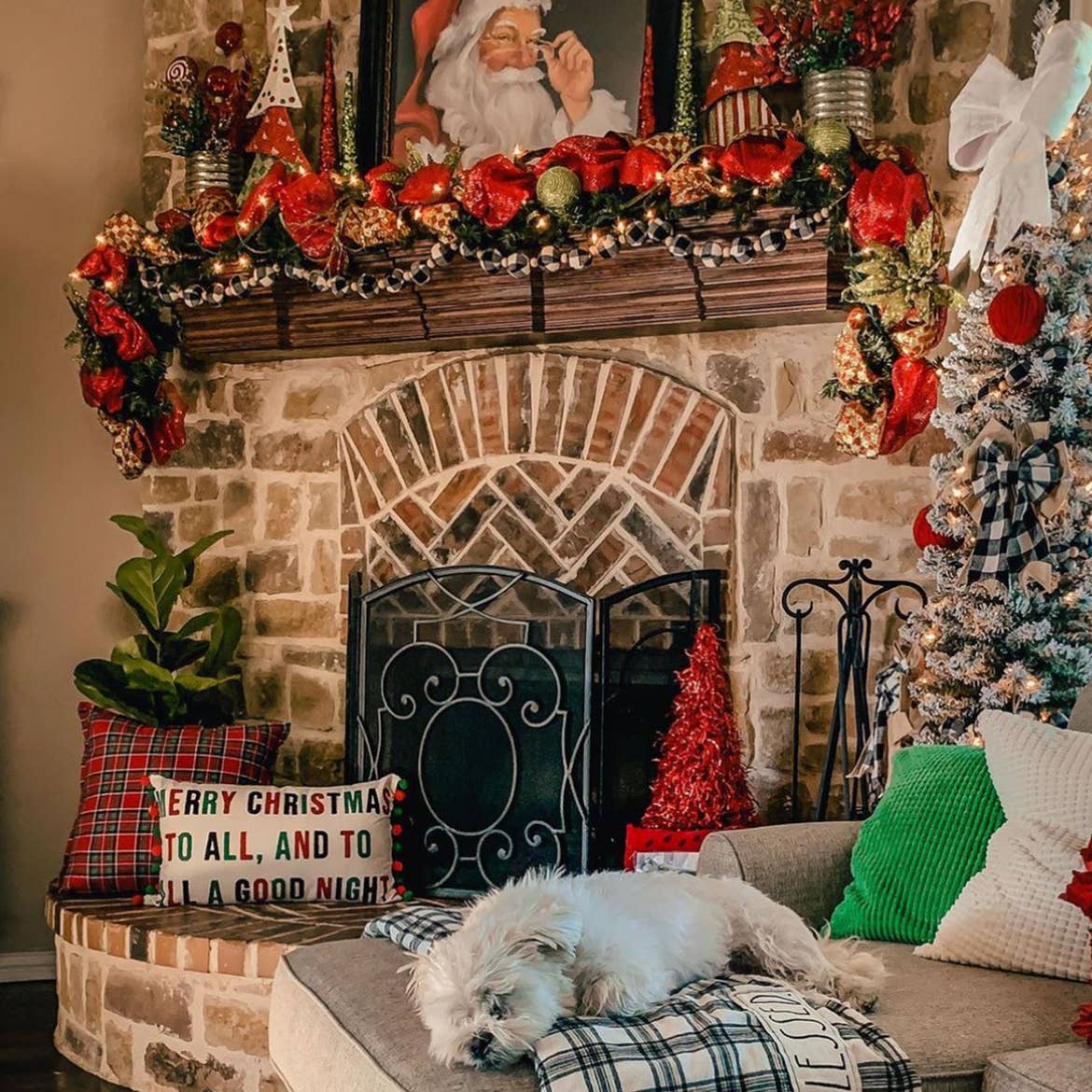A small 'pencil tree' decked out in holiday decor next to a mantle decked out in holiday decor.