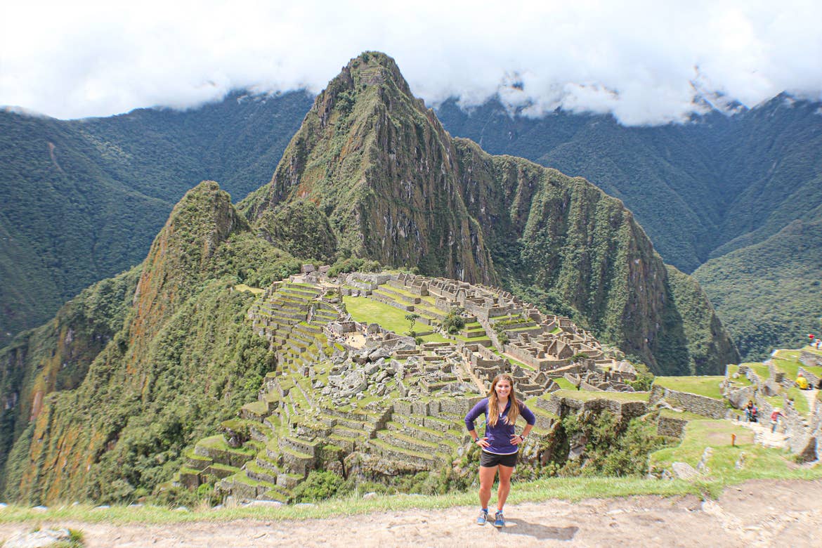 Featured Contributor, Ashlyn George, stands in front of the ruins of an ancient mountain village in Peru.