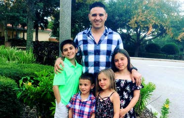 Featured Member, Sara Perezes husband poses with their four children outdoors.