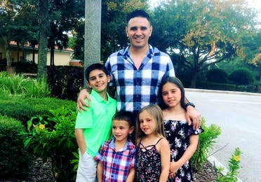 Featured Member, Sara Perezes husband poses with their four children outdoors.