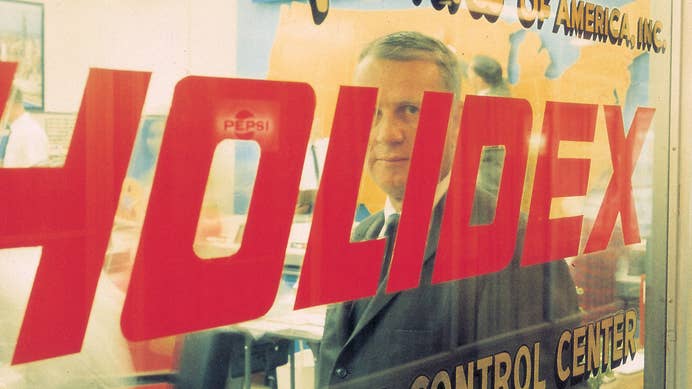 Kemmons Wilson standing behind a window with the Holidex logo