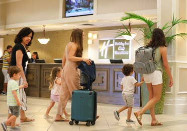 Family of six pulling luggage through lobby of Orange Lake Resort near Orlando, Florida.