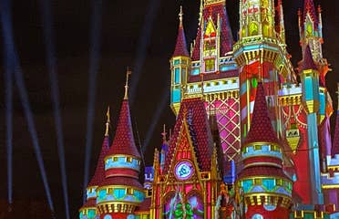 Cinderella's Castle at Magic Kingdom Park at Walt Disney World® Resort is illuminated with holiday projections at night.