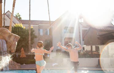 Two kids jumping into outdoor pool at Desert Club Resort in Las Vegas, Nevada.