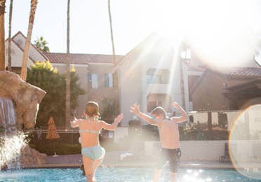 Two kids jumping into outdoor pool at Desert Club Resort in Las Vegas, Nevada.