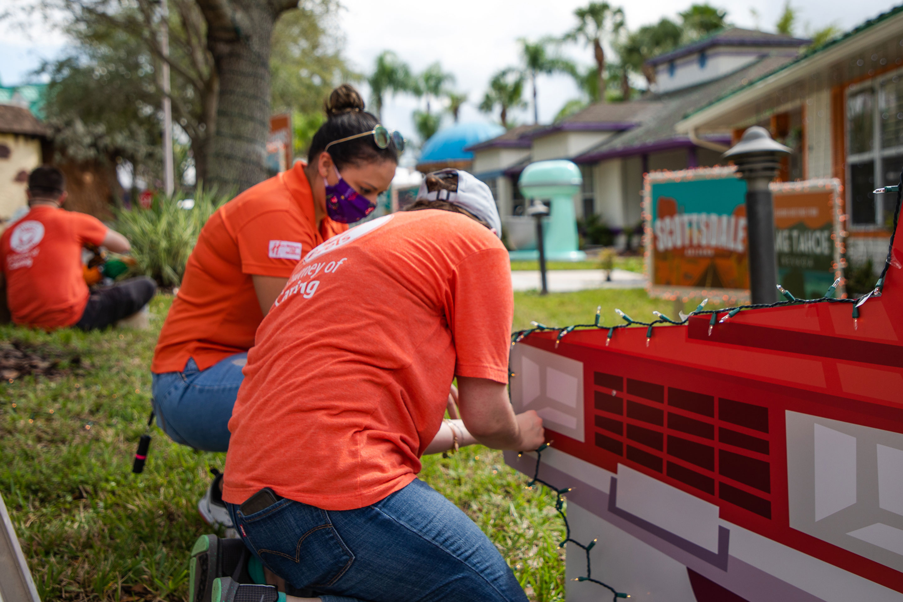 Two HICV Team Members volunteering by adding string lights to our station wagon.