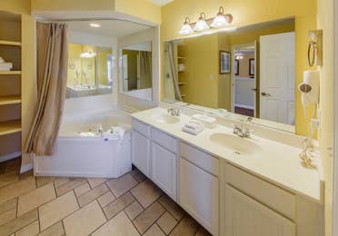 Bathroom with two sinks, large mirror, and shower/tub combination in a presidential two bedroom villa at Piney Shores Resort in Conroe, Texas
