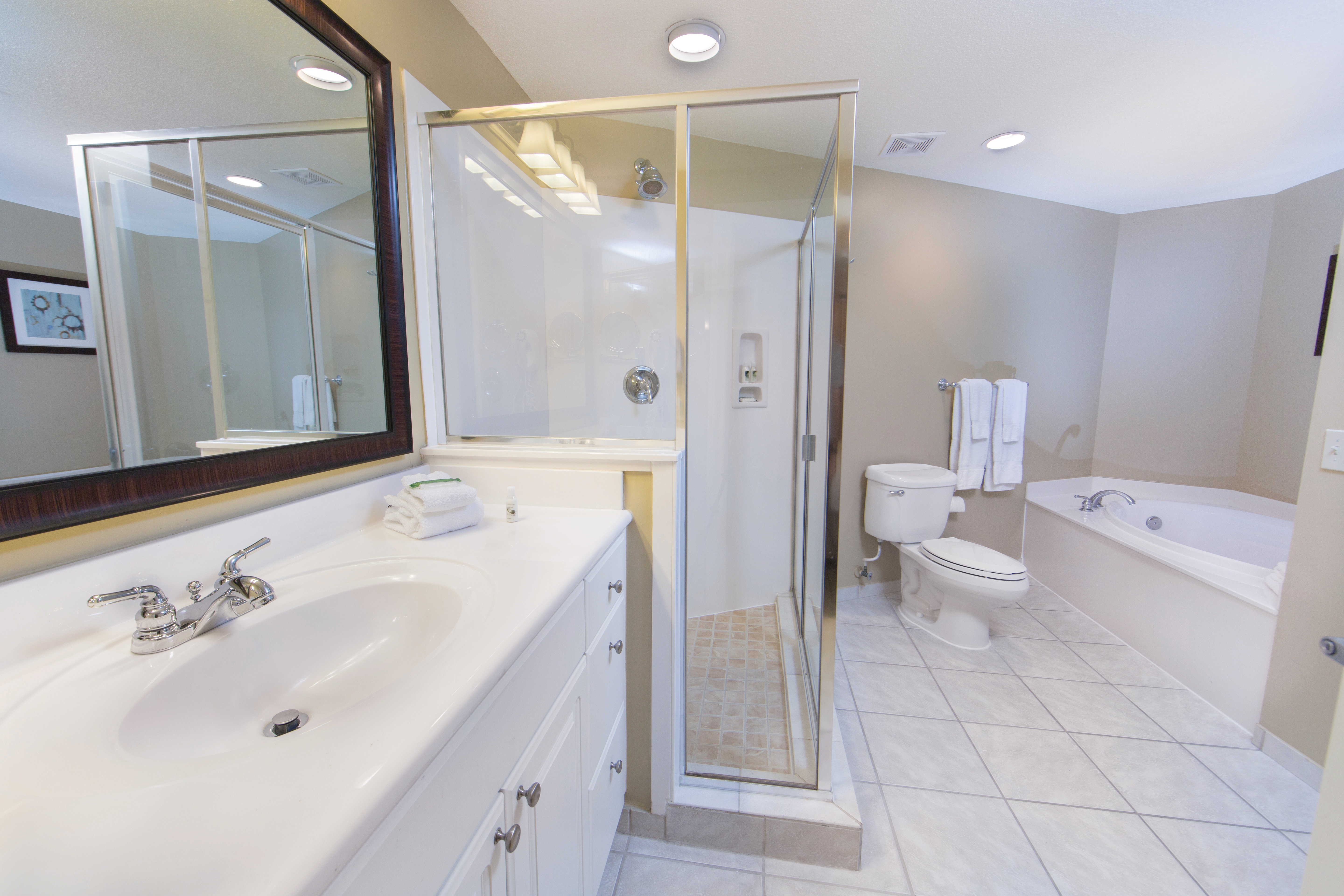Master bathroom with whirlpool tub, walk in shower, toilet and sink with large mirror in a two-bedroom villa at Galveston Beach Resort