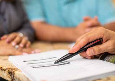 A pen pointing at lines on a contract
