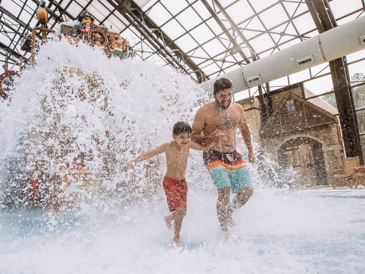 Father and son running through Pirate's Cay Waterpark at Fox River Resort in Sheridan, Illinois.