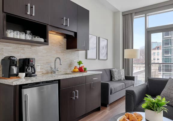 Elegant studio hotel suite with kitchenette, comfortable seating area, and contemporary decor.