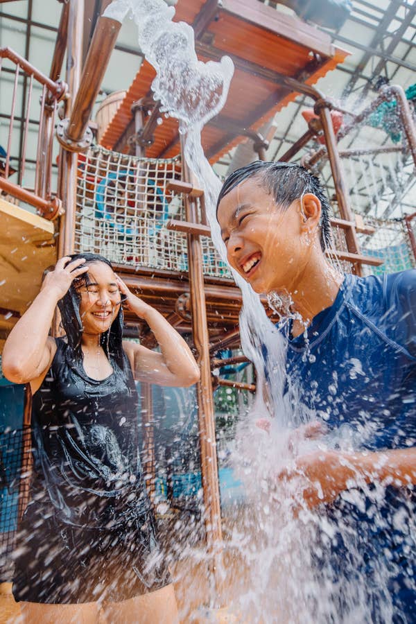 Two children standing under waterfall at Waterpark at the Villages in Flint, Texas.