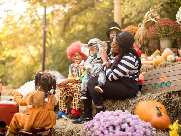 Family in Halloween costumes sitting around pumpkins and other fall decorations.