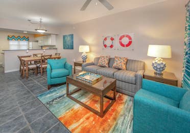 Living room with couch, two accent chairs, and coastal decor in a one-bedroom villa at Panama City Beach Resort